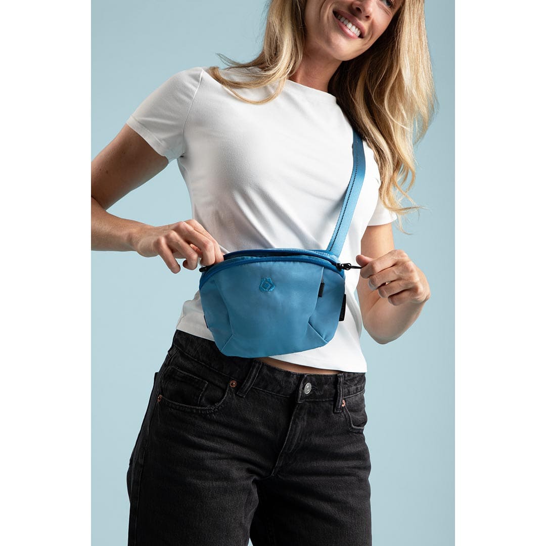 Woman wearing a blue waist bag against a light blue background