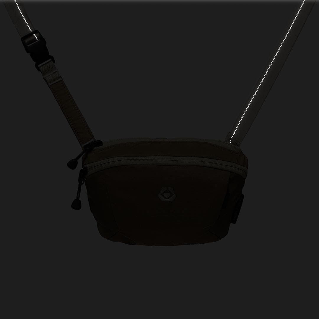 Black waist bag with a strap on a black background
