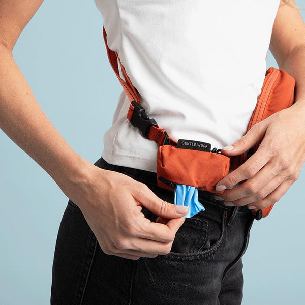 Person wearing an orange waist bag with a blue pouch on a light blue background