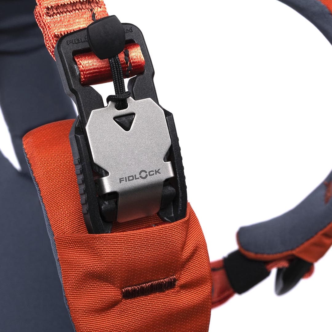 Close-up of an orange strap with a Fidlock lock mechanism on a blurred background