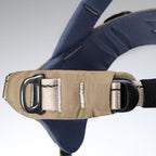 Close-up of a beige seat belt with a black D-ring on a gray background