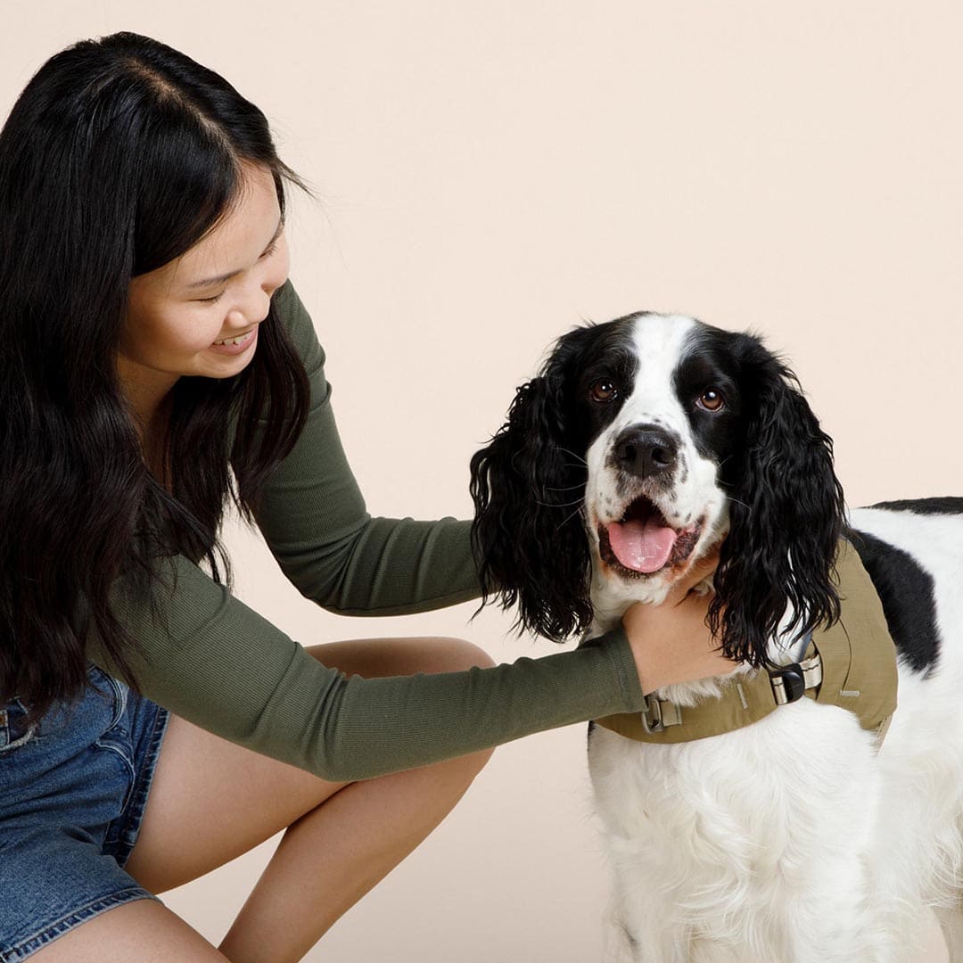 Woman petting a black and white dog on a beige background