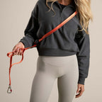 Person holding a red dog leash with a beige background