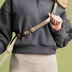 Person wearing a dark gray sweatshirt with a beige strap over a green background
