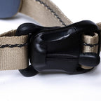 Close-up of a beige dog collar with a black plastic buckle on a white background