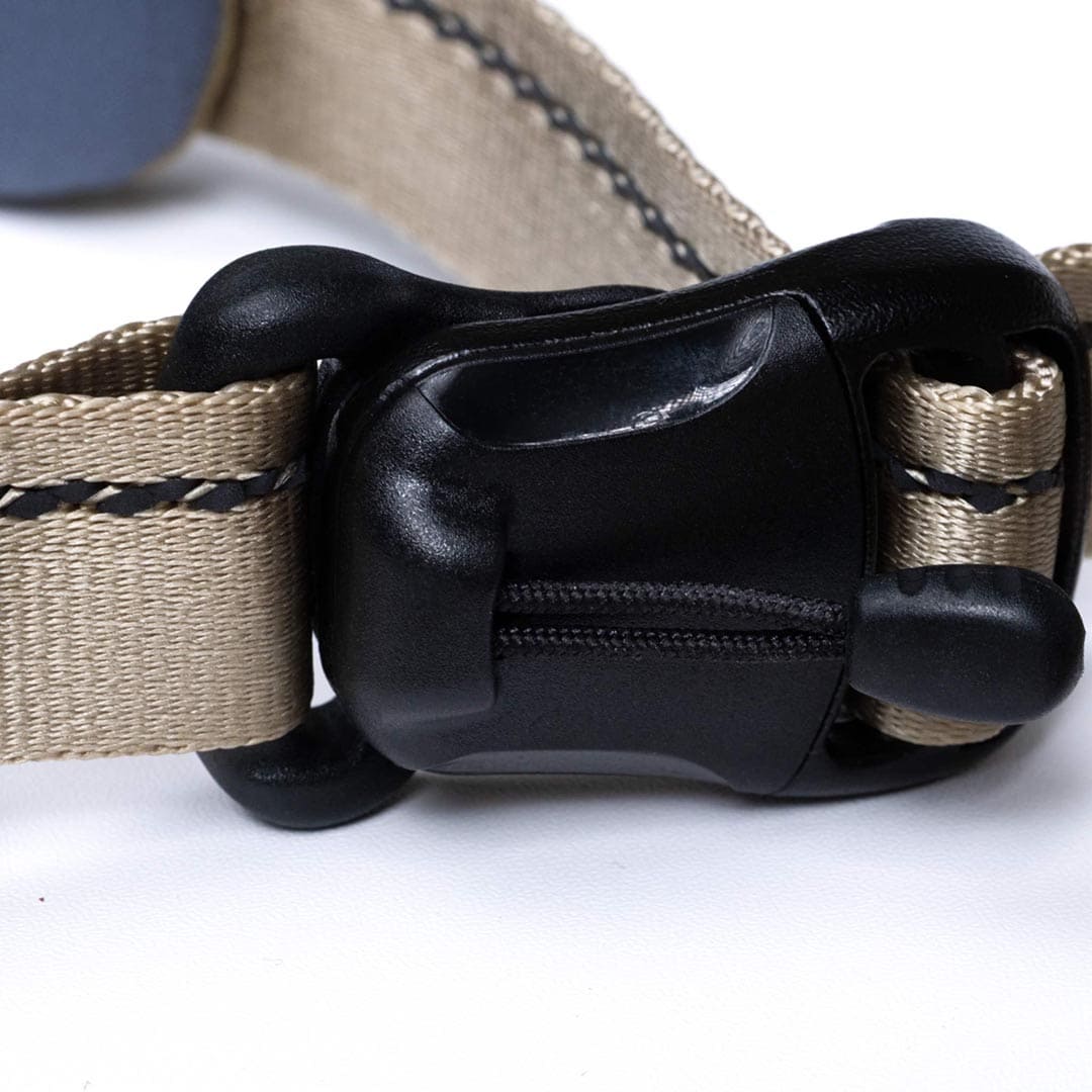 Close-up of a beige dog collar with a black plastic buckle on a white background