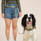 Person wearing a green shirt and blue shorts with a dog on a beige background