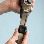 Close-up of a hand holding a quick grip with a black buckle against a light blue background
