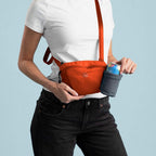 Person wearing an orange crossbody bag with a blue background