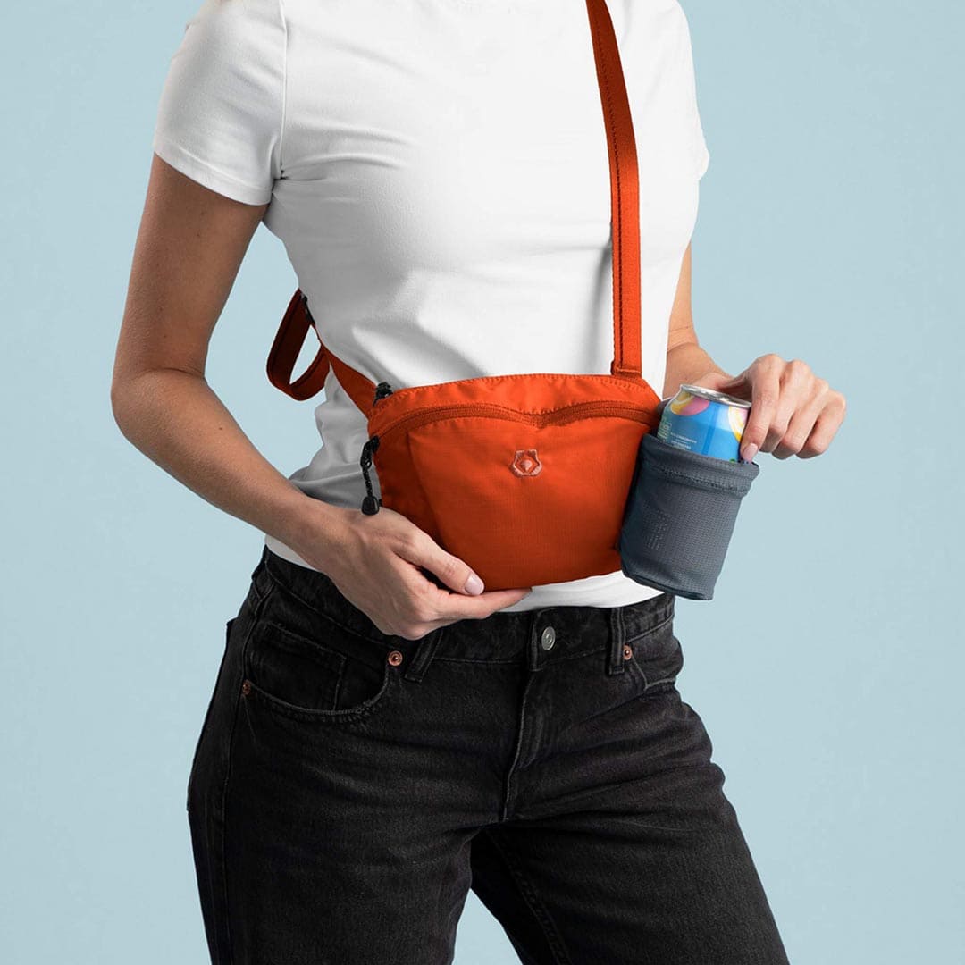 Person wearing an orange crossbody bag with a blue background