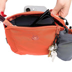 Orange bag with a keychain and phone inside, on a white background