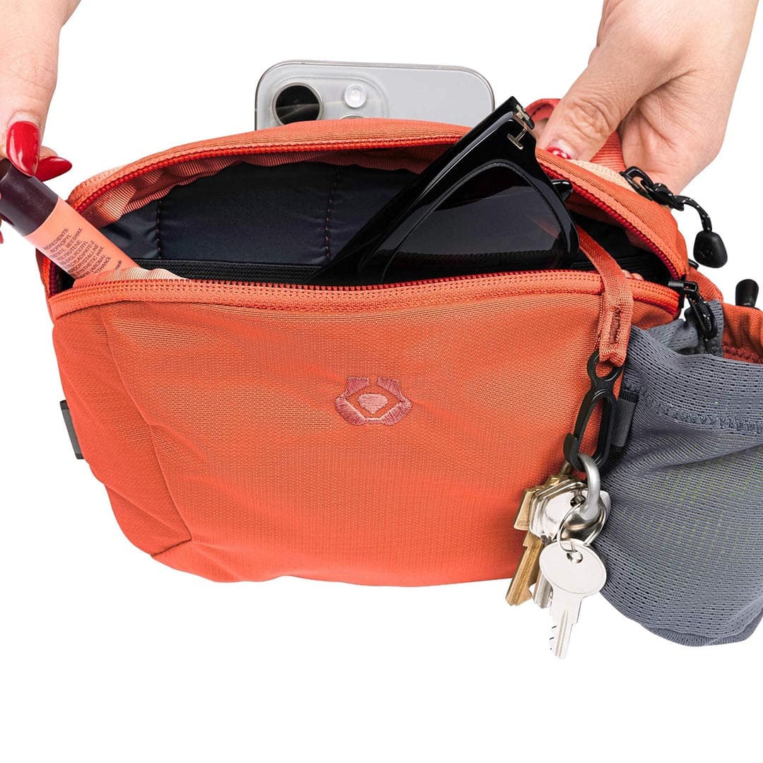 Orange bag with a keychain and phone inside, on a white background