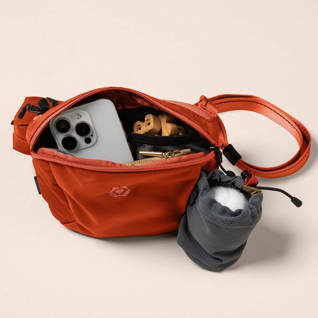 Open red bag with phone, keys, and other items on a beige background