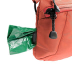 Red backpack with a green trash bag attached to its side on a white background