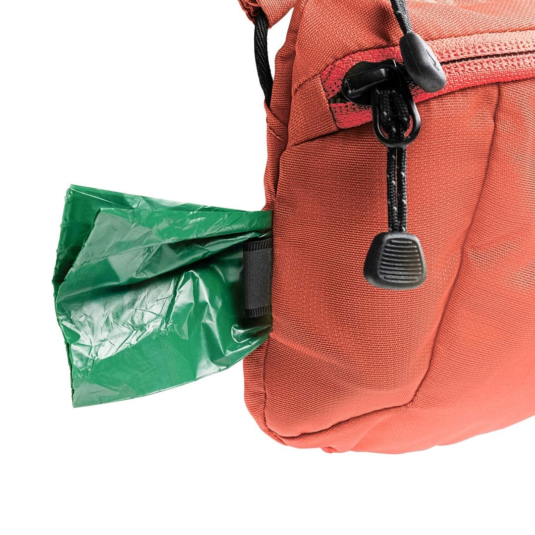 Red backpack with a green trash bag attached to its side on a white background
