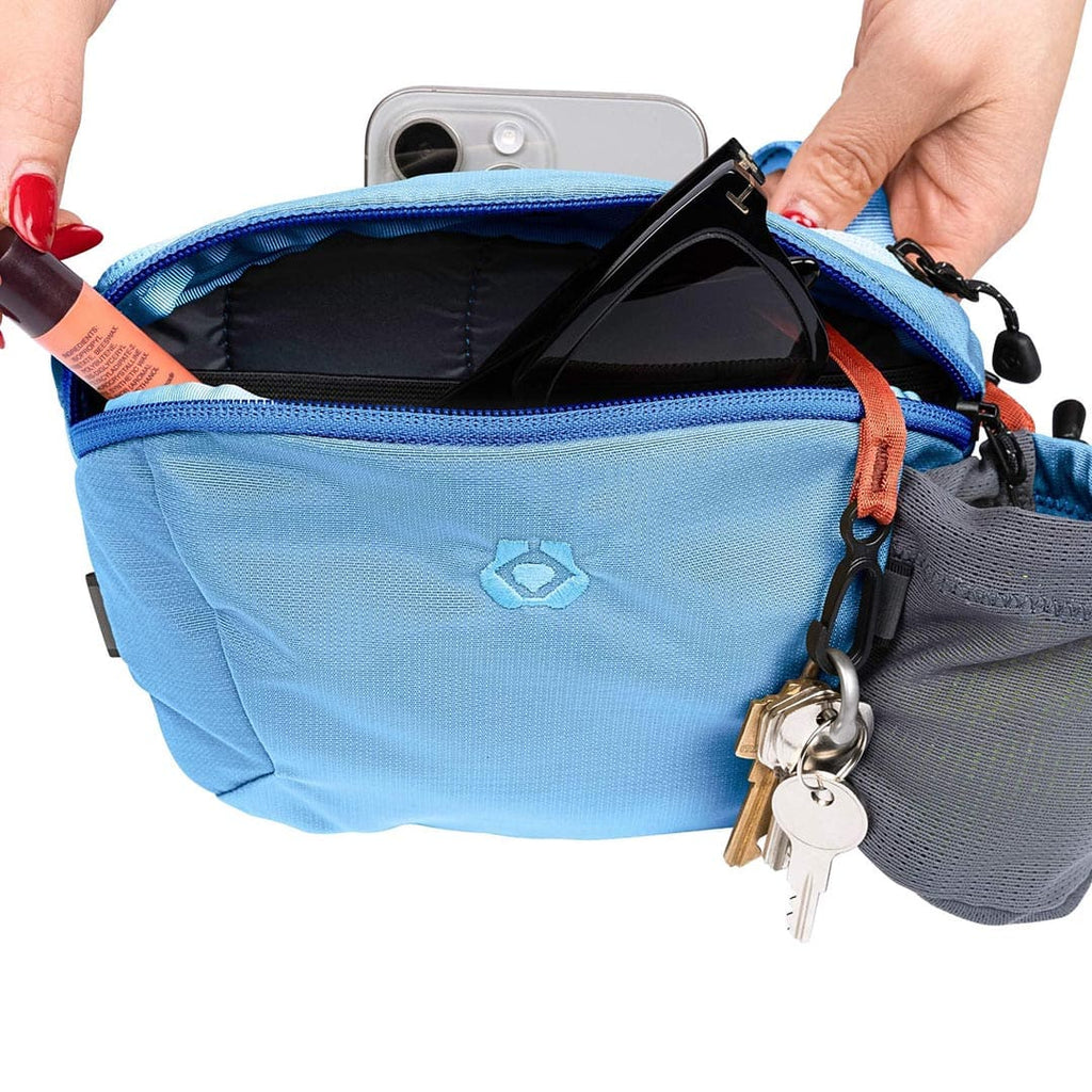 Blue waist bag with a phone and keys, held by a person.