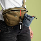 Person wearing a brown crossbody bag with a visible brand logo on a green background