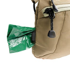 Beige bag with a green trash bag attached to it on a white background